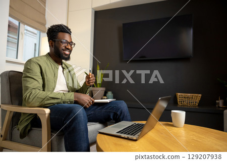 Young businessman having a video call and looking involved Young businessman having a video call and looking involved 129207938