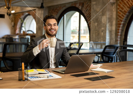 Young caucasian man sitting in the office and having coffee 129208018