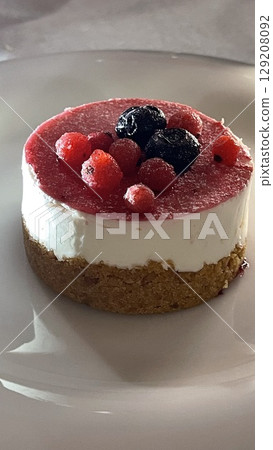 Delicious Berry Topped Cheesecake on a White Plate 129208092