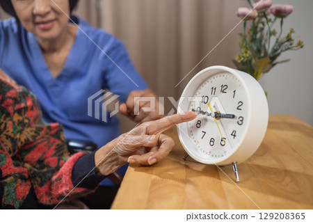 Asian Elderly Woman with Dementia Practicing Read Time on Clock. 129208365