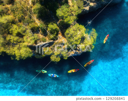 Aerial view of colorful kayaks navigating crystal-clear water 129208841