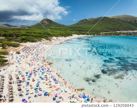 Aerial view of a crowded sandy beach with colorful umbrellas Aerial view of a crowded sandy beach with colorful umbrellas 129208843