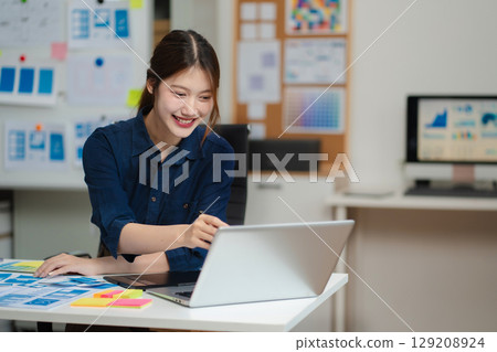 Female coder or developer working using a computer display and smartphone in problem solving at workplace. 129208924