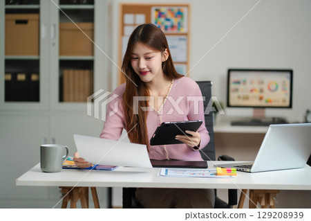 Female coder or developer working using a computer display and smartphone in problem solving at workplace. 129208939