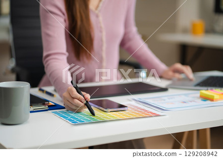 Female coder or developer working using a computer display and smartphone in problem solving at workplace. 129208942