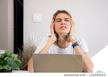 Unhappy young caucasian businesswoman using laptop computer on desk with stress and burnout. Unhappy young caucasian businesswoman using laptop computer on desk with stress and burnout. 129209229