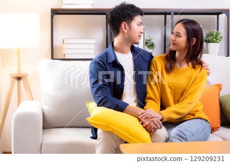Portrait young asian couple hold hands sitting on sofa looking affectionate and embrace. Portrait young asian couple hold hands sitting on sofa looking affectionate and embrace. 129209231