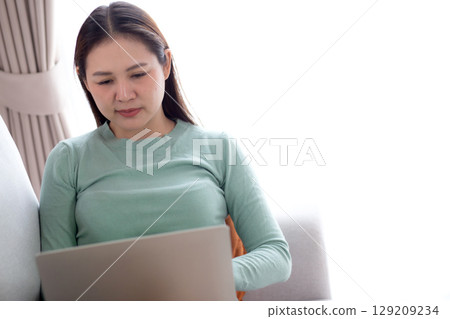 Young asian business woman sitting on sofa using laptop computer in living room at home. 129209234