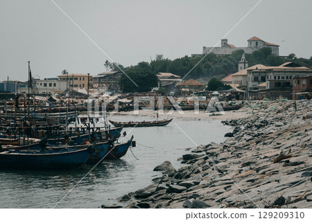 The fisherman wooden boats on the coast of Elmina, Ghana, a historic West African town, famous for fishing community, with the old fort on the hill. 129209310