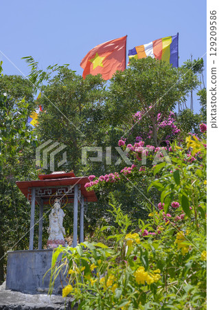 Flags of Vietnam and Buddhism fly over a tropical garden and sculpture at Hua Da Boo Monastery 129209586