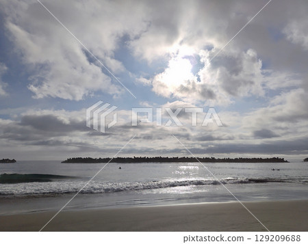 The sun hidden behind clouds reflected on the sea The sun hidden behind clouds reflected on the sea 129209688