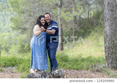A man and woman are standing in a field, smiling and holding hands 129209960