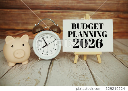 Budget Planning 2026 text message with alarm clock and piggy saving on wooden background 129210224