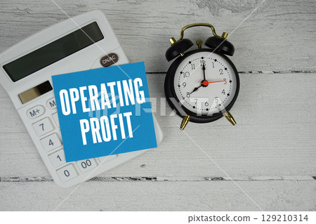 Operating Profit text with calculator and alarm clock  on wooden background 129210314