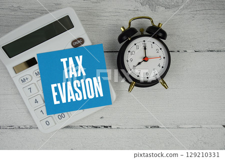 Tax Evasion text with calculator and alarm clock on wooden background Tax Evasion text with calculator and alarm clock on wooden background 129210331