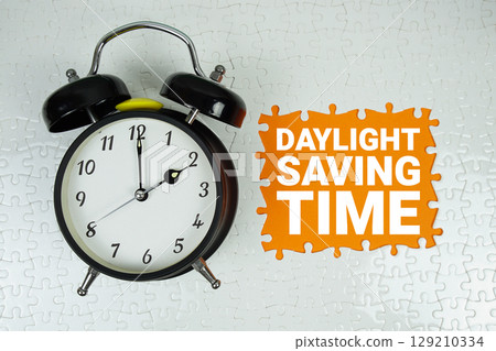 Daylight Saving Time text with alarm clock on orange background Daylight Saving Time text with alarm clock on orange background 129210334