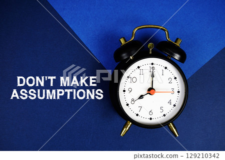 Don't Make Assumptions text with alarm clock on blue background Don't Make Assumptions text with alarm clock on blue background 129210342