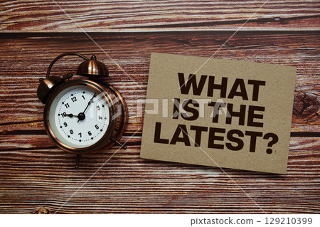 What Is The Latest? text with alarm clock on wooden background What Is The Latest? text with alarm clock on wooden background 129210399
