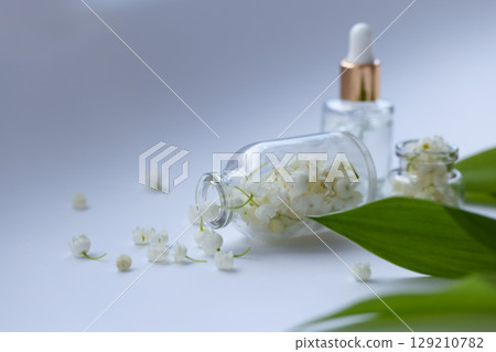 Glass bottle of lily of the valley essential oil with fresh flowers 129210782
