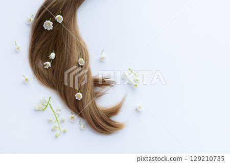 Female hair with white merry bells flowers. Closeup, on a white background. 129210785