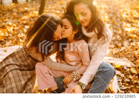 The homosexual family playing with her daughter in the autumn forest. The adventure is more fun. The homosexual family playing with her daughter in the autumn forest. The adventure is more fun. 129210905