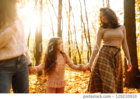 The homosexual family playing with her daughter in the autumn forest. The adventure is more fun. The homosexual family playing with her daughter in the autumn forest. The adventure is more fun. 129210910
