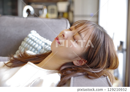 Young woman lying down on the sofa 129210932