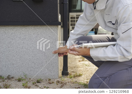 A man checking the foundations of a house A man checking the foundations of a house 129210968