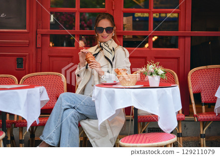 Stylish woman drinking coffee at Montmartre cafe terrace in Paris Stylish woman drinking coffee at Montmartre cafe terrace in Paris 129211079