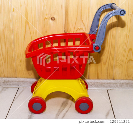 Toy shopping cart on the wooden background Toy shopping cart on the wooden background 129211231