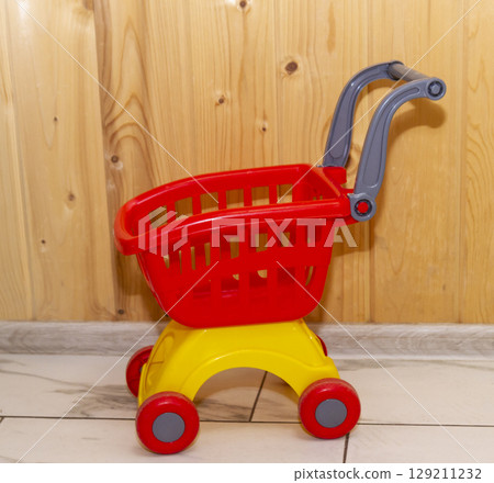 Toy shopping cart on the wooden background  129211232