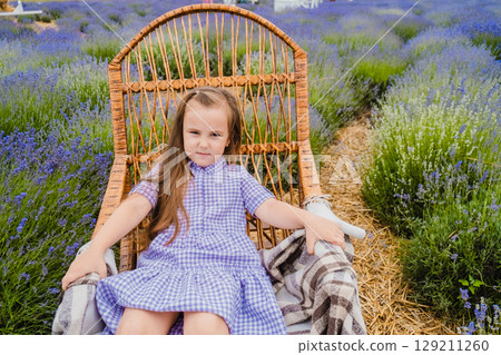 The delicate purple shade of the girl's dress echoes the color of the lavender among which she is sitting in the rocking chair The delicate purple shade of the girl's dress echoes the color of the lavender among which she is sitting in the rocking chair 129211260