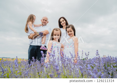 The mother and her daughters, dressed in white dresses, stand in the purple lavender field The mother and her daughters, dressed in white dresses, stand in the purple lavender field 129211314