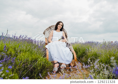 A young woman enjoys the silence and beauty of the lavender field 129211328