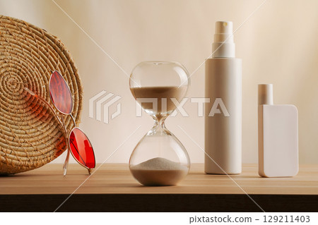 Elegant arrangement of an hourglass, sunglasses, and cosmetic spf bottles on a simple beige backdrop. Lowkey natural concept of summer luxury skincare and protection, warm tone minimalist muted photo Elegant arrangement of an hourglass, sunglasses, and cosmetic spf bottles on a simple beige backdrop. Lowkey natural concept of summer luxury skincare and protection, warm tone minimalist muted photo 129211403