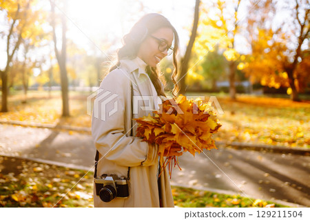 Woman taking pictures in autumn forest. Smiling woman enjoying autumn weather. Lifestyle concept. 129211504