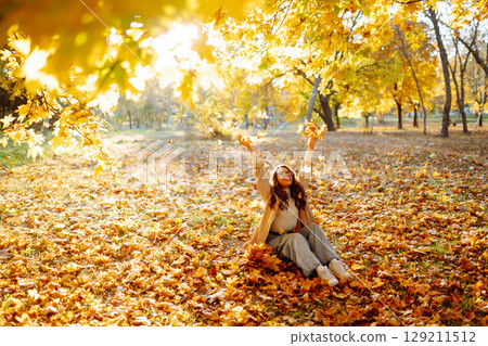 Young woman taking pictures in the autumn forest. Lady Walking In Fall Park With Yellow Foliage. 129211512