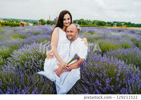 In the middle of the lavender field, a young couple in love enjoys the moment In the middle of the lavender field, a young couple in love enjoys the moment 129211522