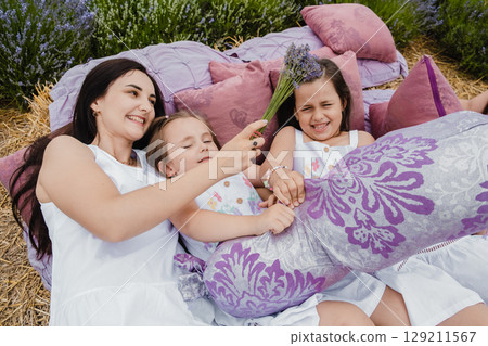 The happy mother and her three daughters snuggle close to each other, creating a perfect family scene The happy mother and her three daughters snuggle close to each other, creating a perfect family scene 129211567
