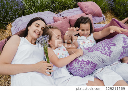 The family enjoys a moment of relaxation in the lavender field The family enjoys a moment of relaxation in the lavender field 129211569