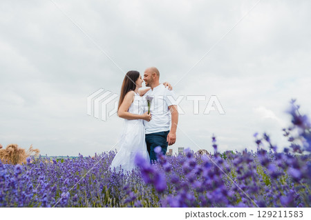 A field of lavender spreads around a couple in love A field of lavender spreads around a couple in love 129211583