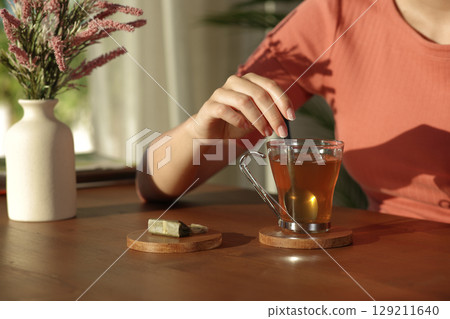 Woman hand throwing sugar in a coffee cup at home Woman hand throwing sugar in a coffee cup at home 129211640