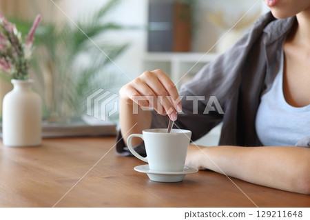 Woman hand throwing sugar in a coffee cup at home 129211648
