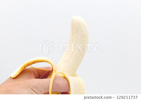 Peeled banana in hand Peeled banana in hand 129211737