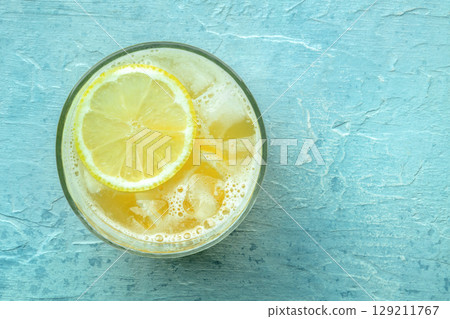 A glass of fresh lemonade, a mocktail with lemon juice, on a blue background 129211767
