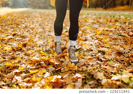 Female legs in boots walking through fallen trees in autumn park. Nature, travel concept. 129211841