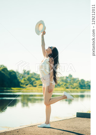 The blonde girl raised her hat up as if trying to touch the sky 129212011