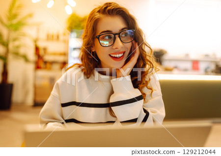 Young woman sitting on cafe with laptop. Beautiful college student on a cafe. Concept for education 129212044