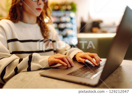 A young woman is engaged in typing on a laptop. Cyber security. Business, Freelance, Shopping 129212047