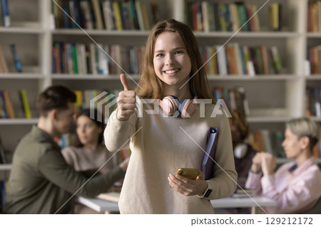 Happy female student looking at camera showing thumb up Happy female student looking at camera showing thumb up 129212172